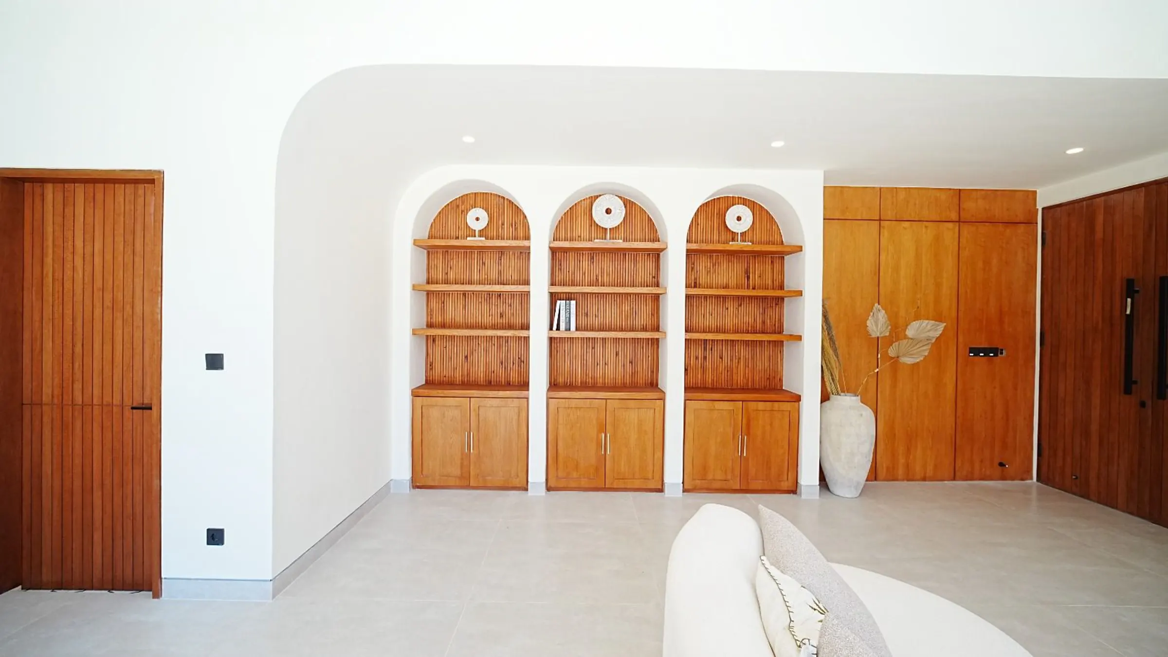 Built-in arched teak cabinets in a white living room in Bali