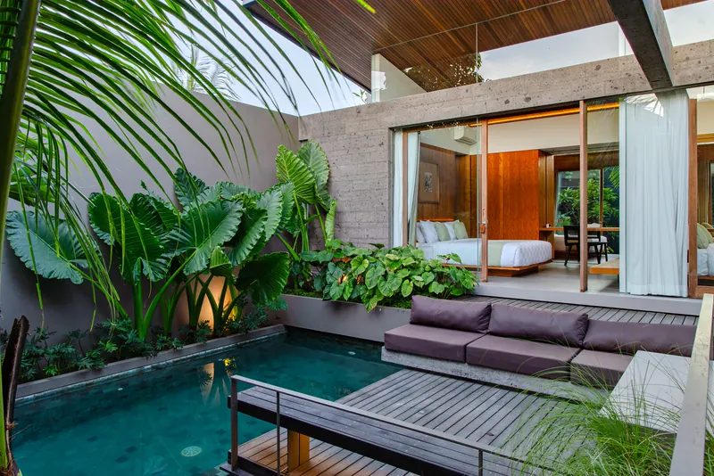 Courtyard pool villa in Bali with tropical planting, timber decks and glass bedrooms opening onto the water
