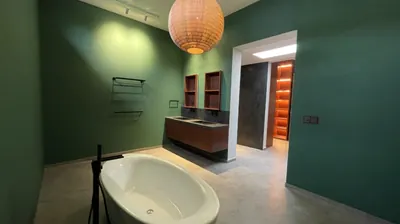 Deep green bathroom with a freestanding bathtub and rattan pendant light in Bali