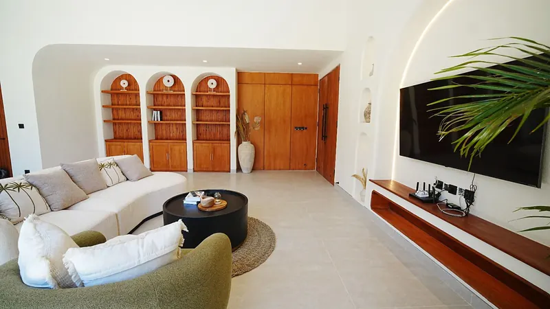 Cream living room in Bali with arched teak shelving and a curved sofa