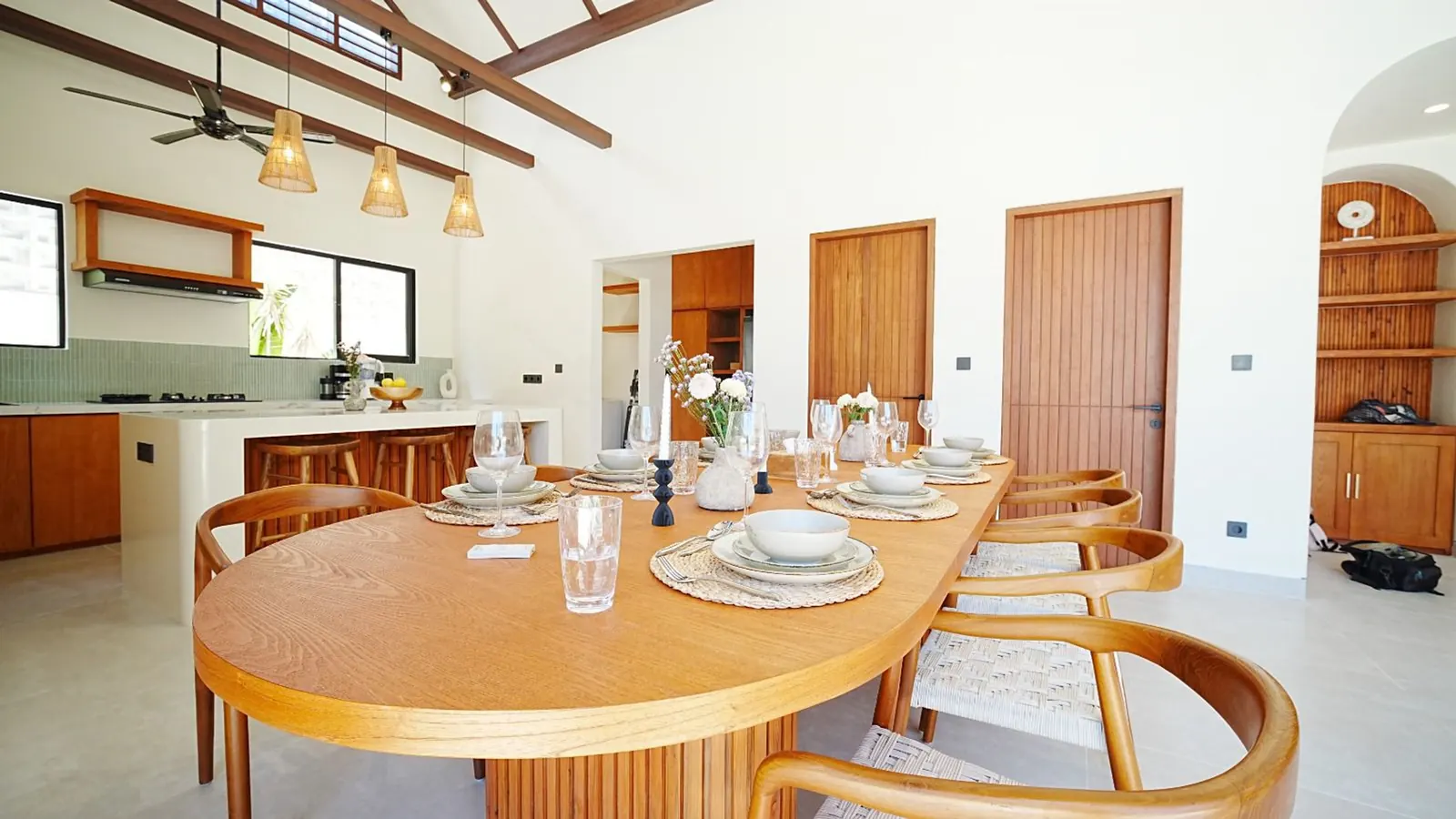 An oval dining table set beneath rattan pendants