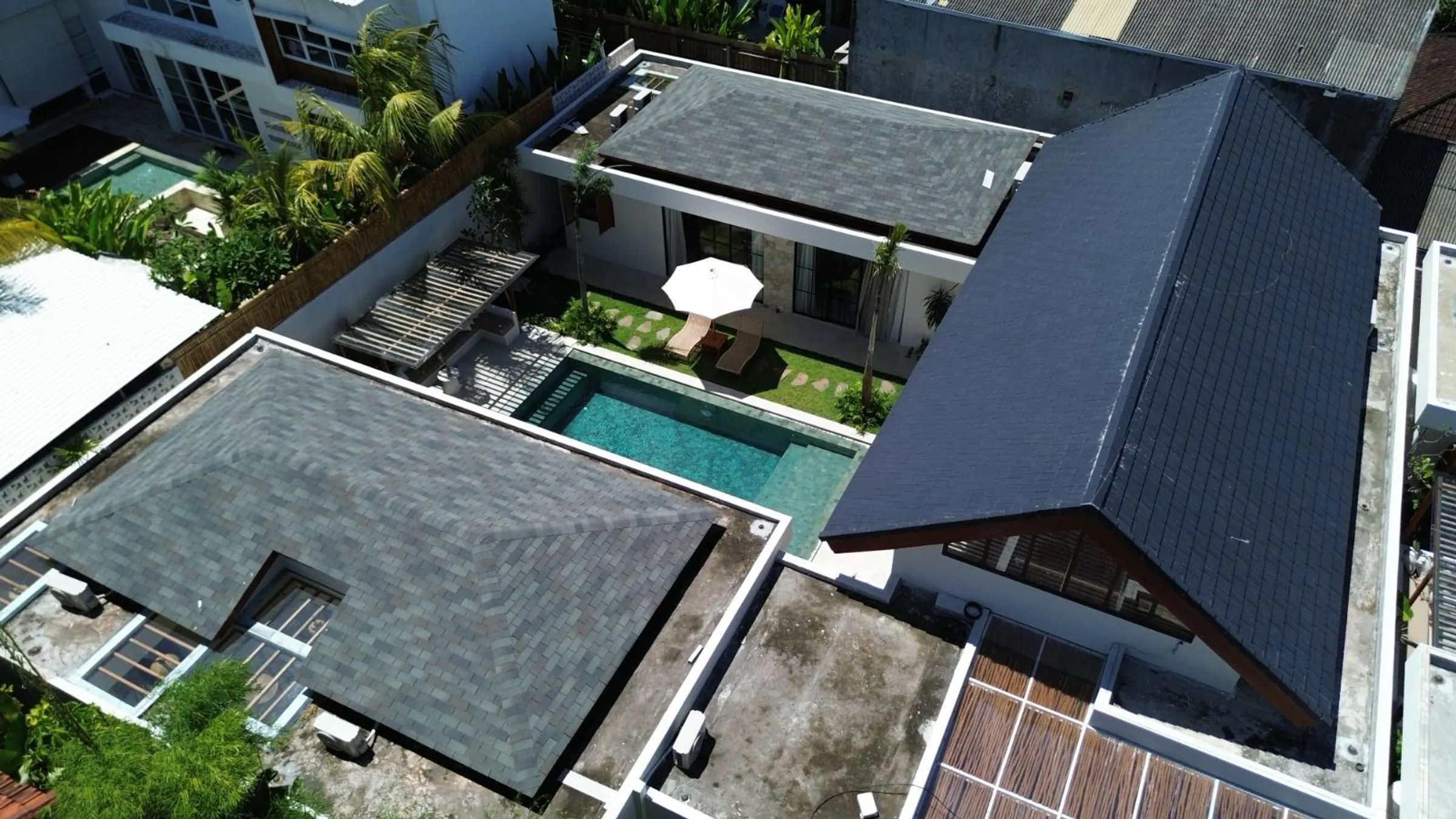 Aerial view of pitched villa roofs around a courtyard pool in Bali