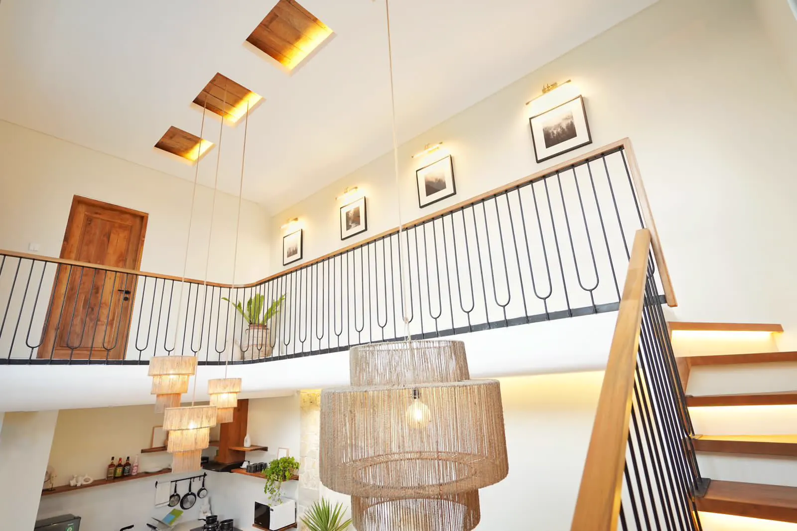 A double height living space with a timber staircase and woven rattan pendants
